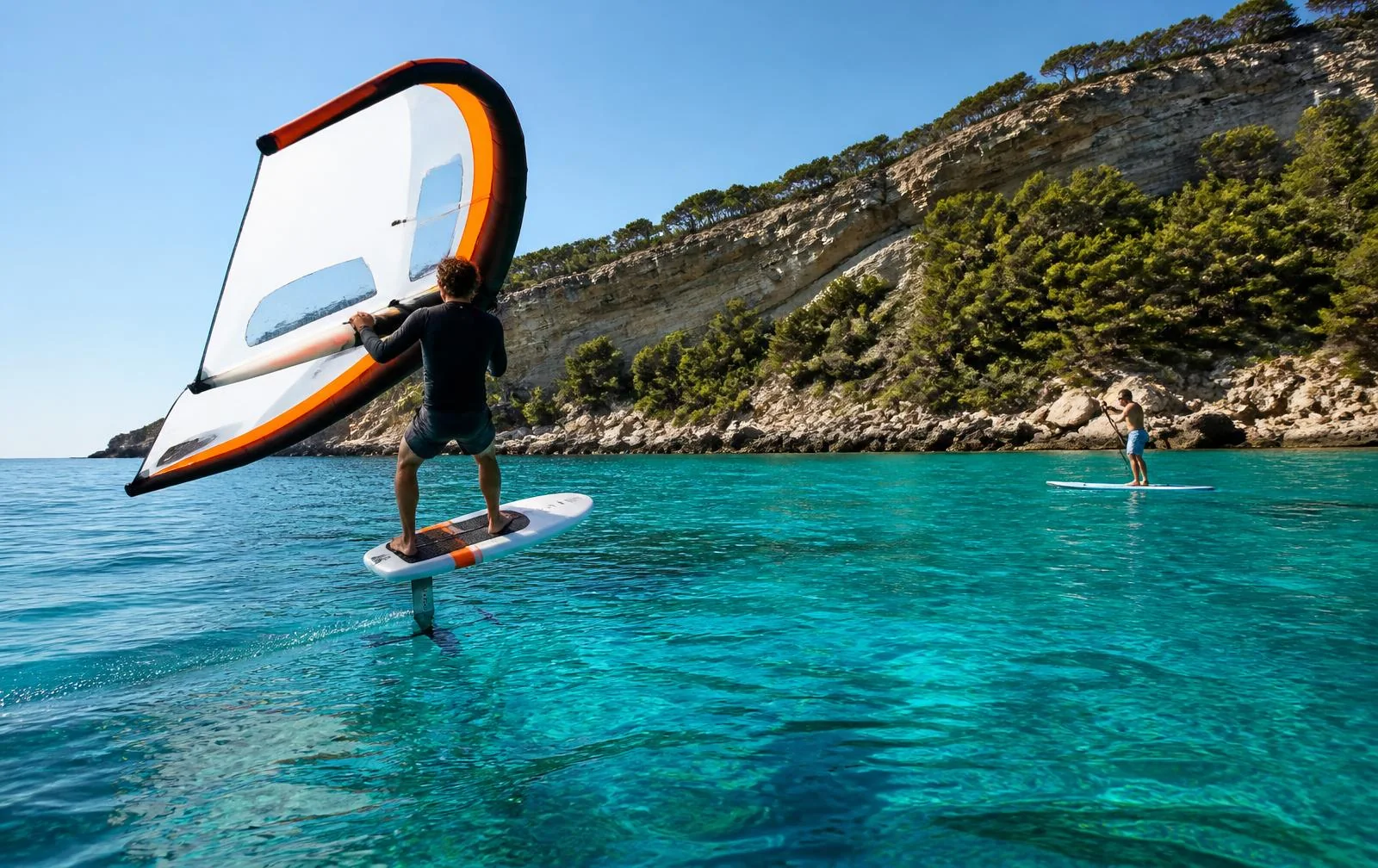 Wingfoiler und Stand-up-Paddler in einer klaren Felsbucht auf Mallorca
