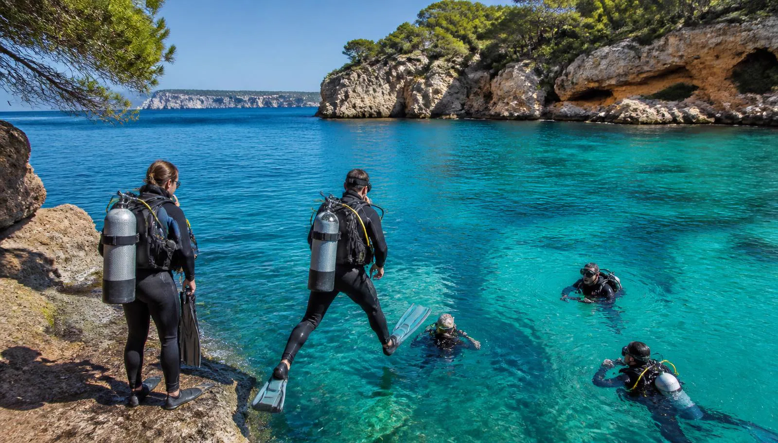 Taucher beim Einstieg in das klare Wasser einer Felsbucht bei Cala d’Or auf Mallorca