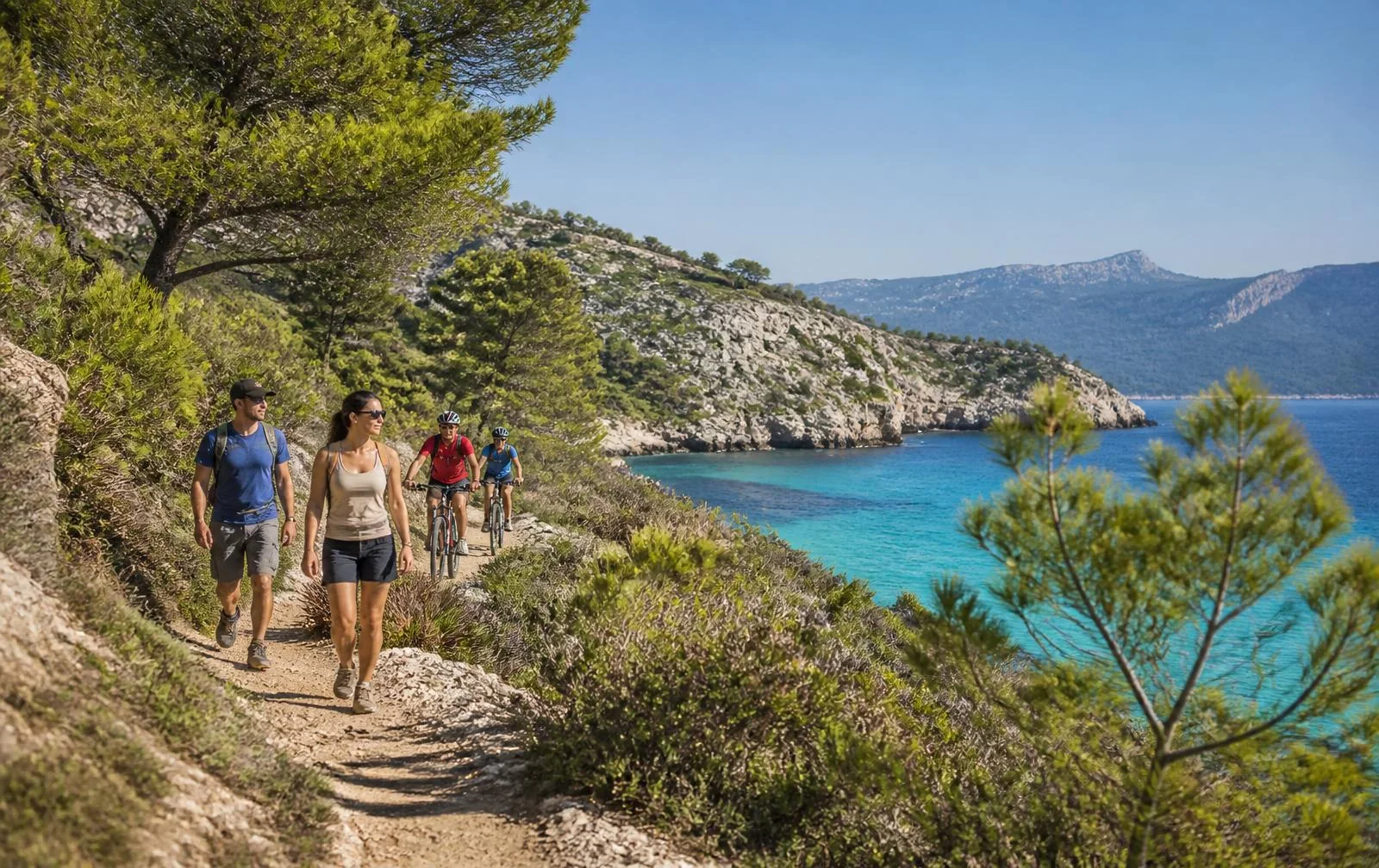 Aktive Urlauber beim Wandern und Radfahren an einer felsigen Bucht auf Mallorca
