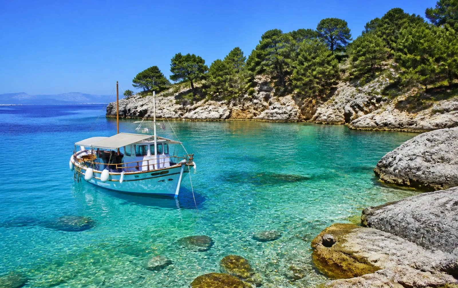 Ausflugsboot in einer türkisen Bucht des Nationalparks Cabrera vor felsiger, pinienbewachsener Küste
