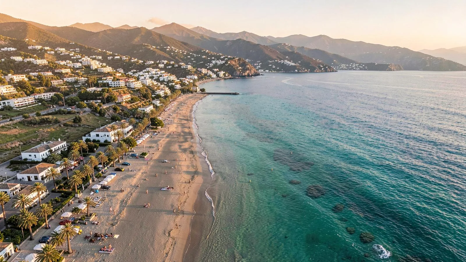 Langer Sandstrand von Cala Millor an Mallorcas Ostküste mit Palmenpromenade, Hotelzeile und flach auslaufendem Wasser