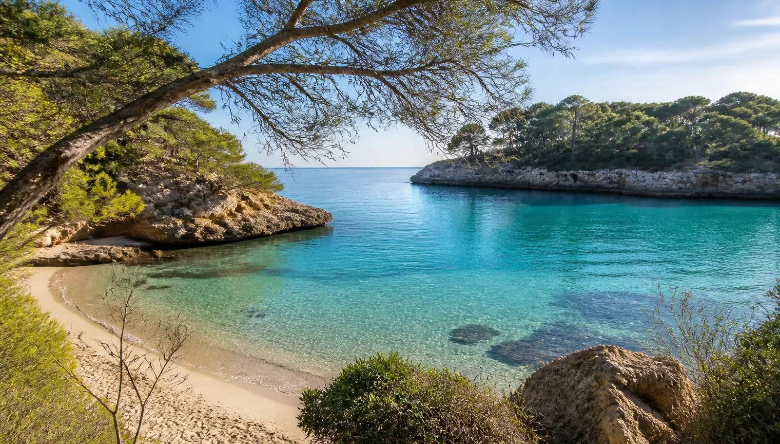 Cala Mondragó auf Mallorca: Sandbucht im Naturpark zwischen bewaldeten Felsen