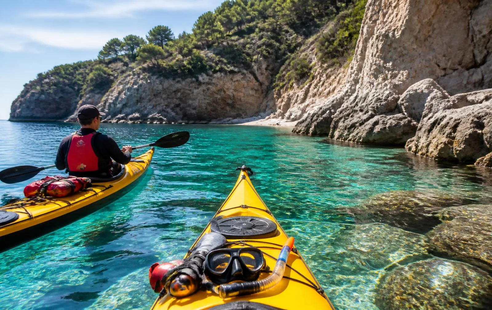Zwei Seekajaks mit Schnorchelausrüstung vor einer Felsküste mit klarem türkisem Wasser auf Mallorca
