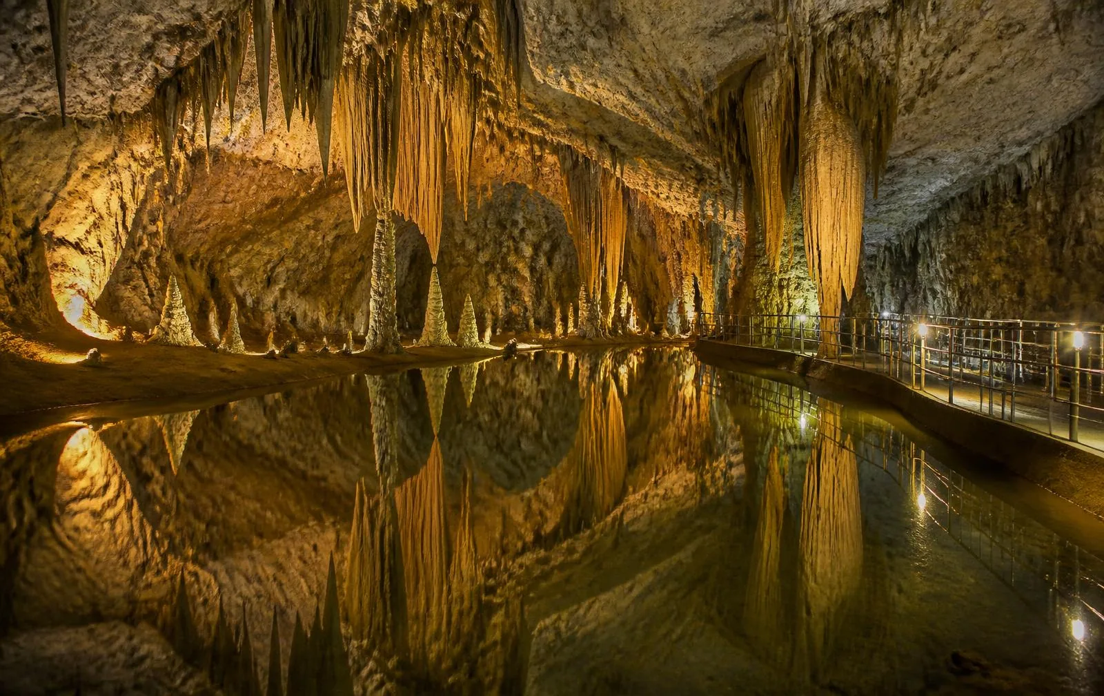 Beleuchtete Tropfsteinformationen über einem unterirdischen See in einer Höhle bei Porto Cristo
